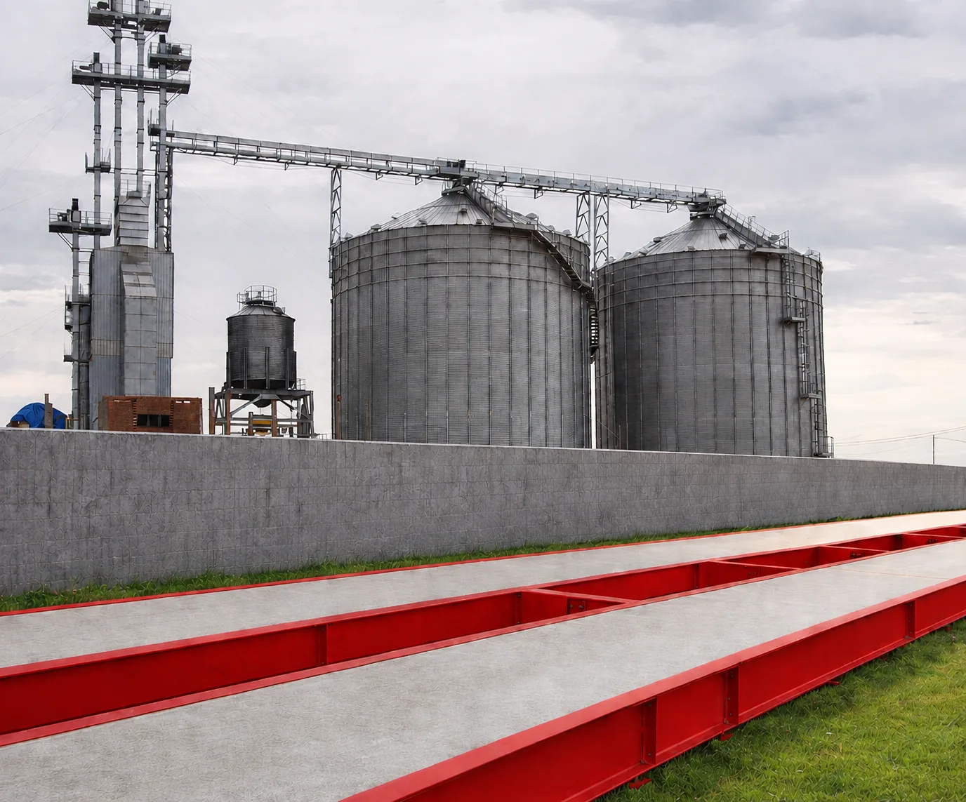 Plataforma de pesagem de concreto com estrutura vermelha instalada junto a silos